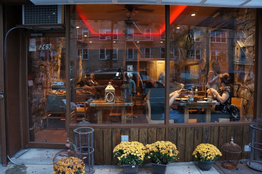 Toné Café's front windows on Neptune Avenue, Brighton Beach, with mums along the sidewalk