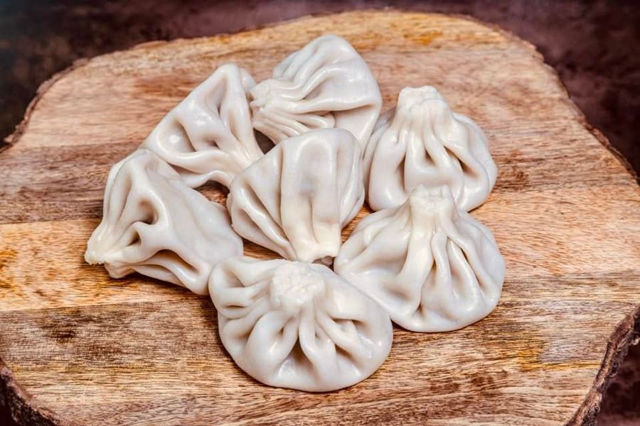 Hand-pleated khinkali dumplings on a wooden board at Toné Café