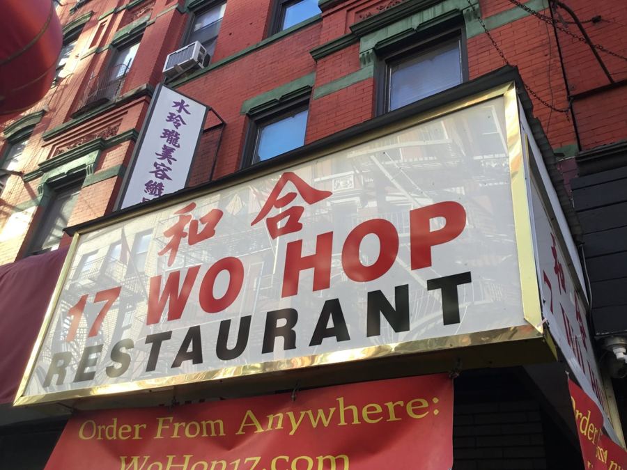 The white-and-red '17 Wo Hop Restaurant' sign with Chinese characters hangs over Wo Hop's red-brick storefront on Mott Street in Chinatown.