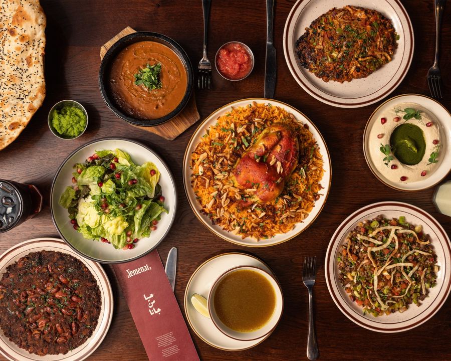 A table spread at Yemenat: roast lamb over spiced rice with almonds, salad, soups, flatbread and sauces in Bay Ridge