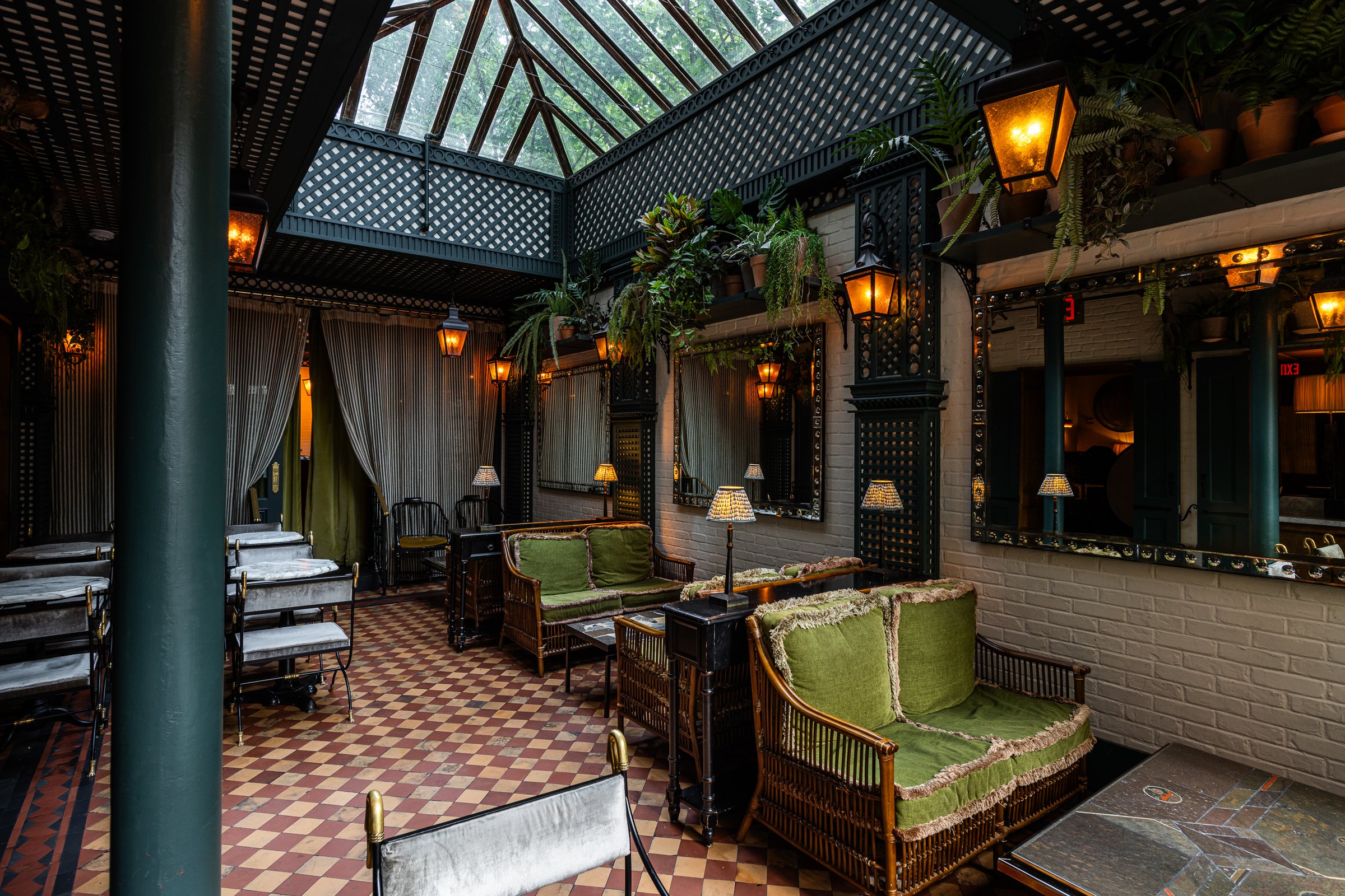 The glass-roofed patio off Hotel Chelsea's Lobby Bar, green velvet sofas and lanterns under a trellis of plants