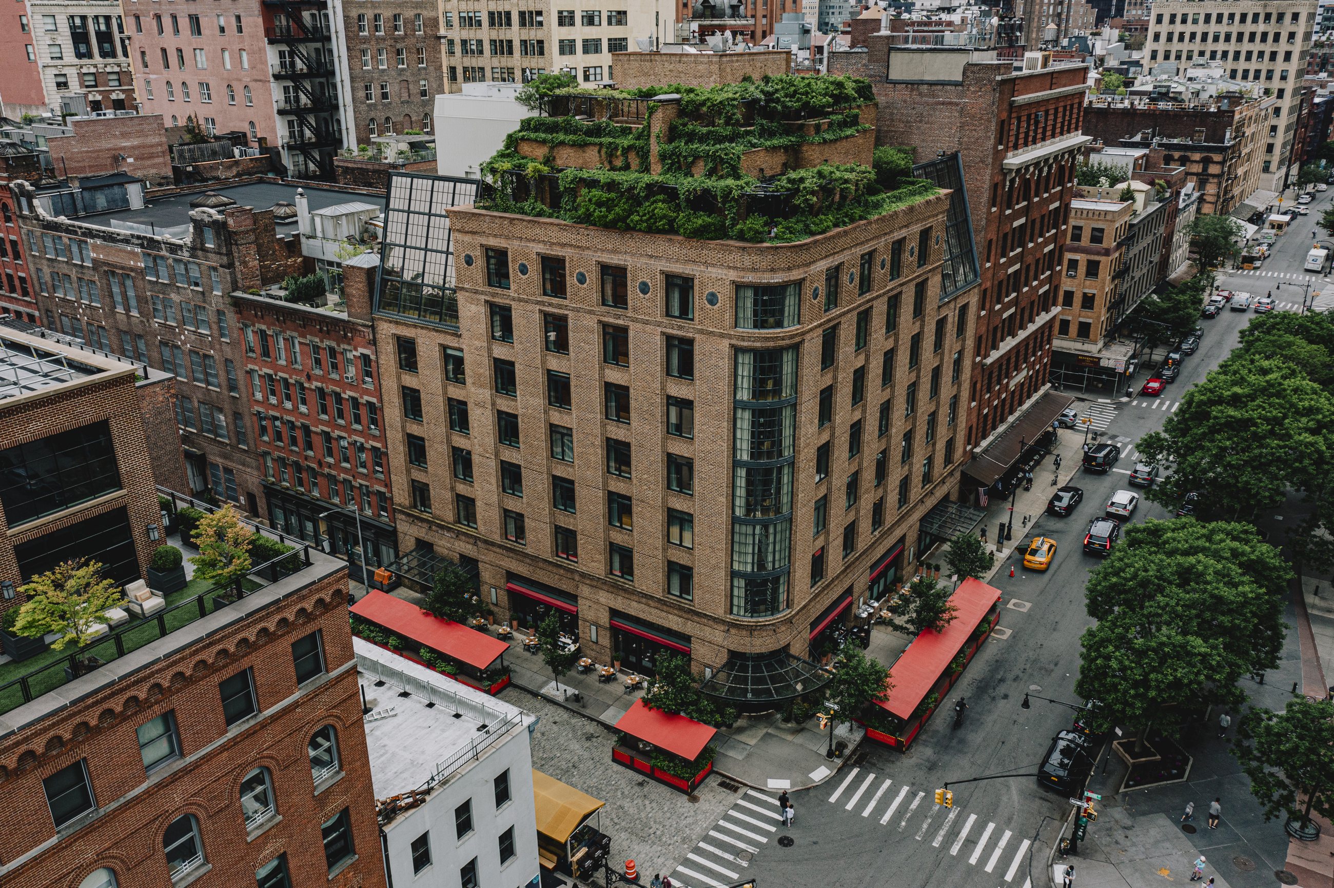 The Greenwich Hotel seen from above: its brick corner, red awnings and the overgrown rooftop garden in Tribeca
