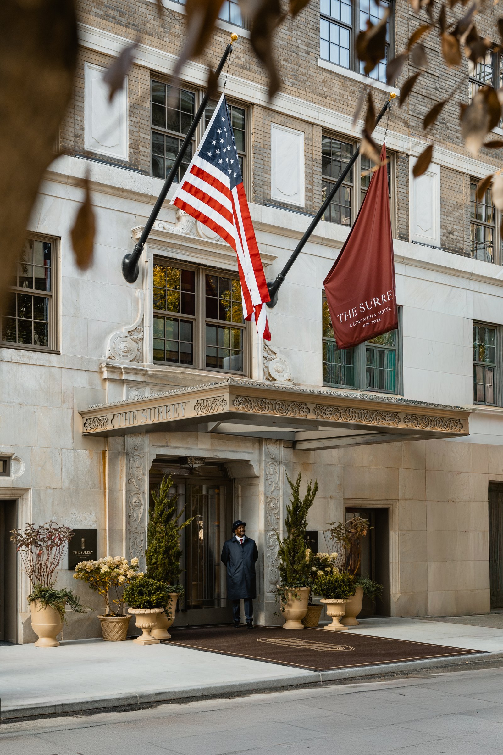The Surrey's limestone entrance on East 76th Street, flags above the canopy and a doorman at the door