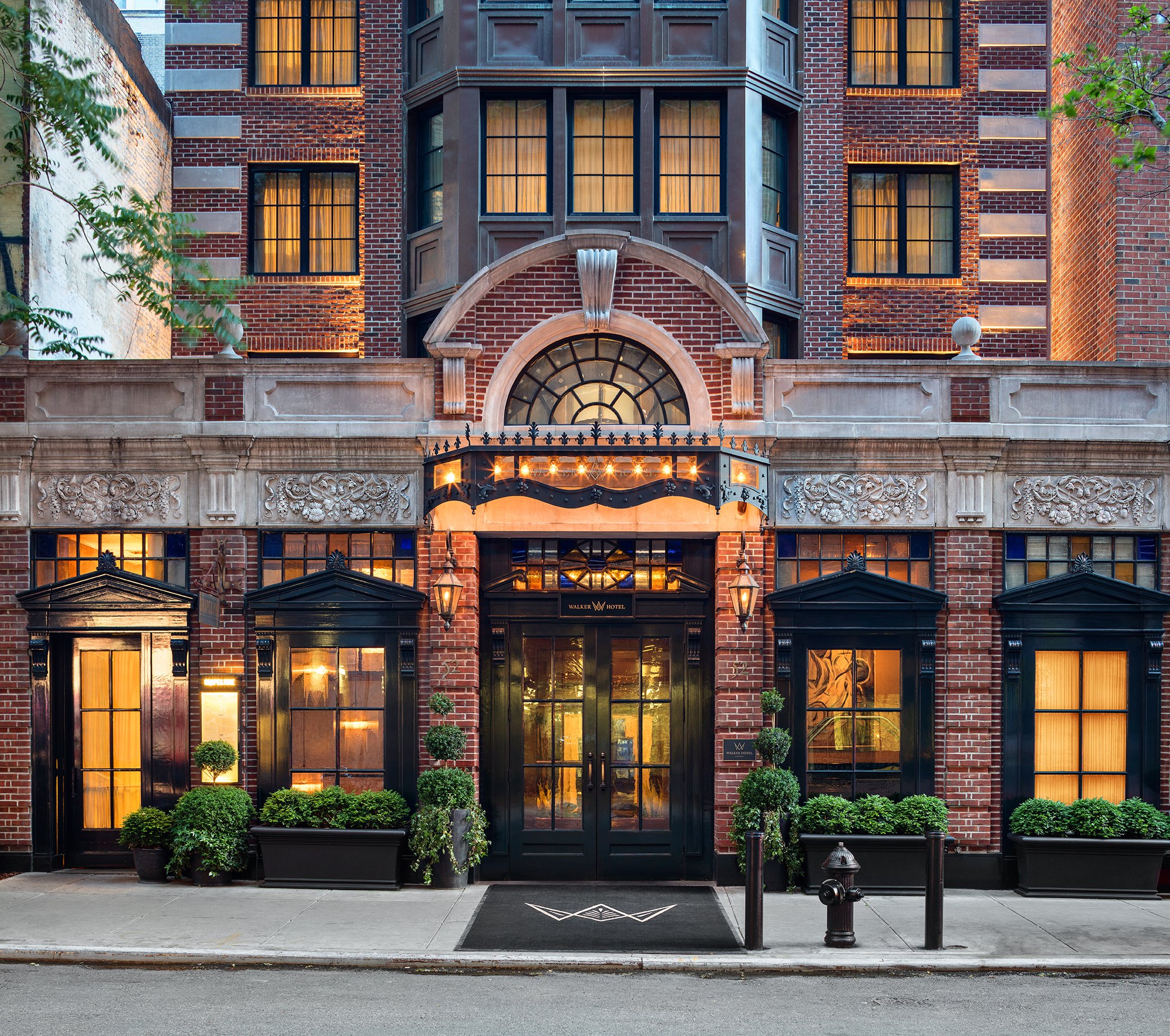 Walker Hotel Greenwich Village's brick and limestone facade lit at dusk on West 13th Street