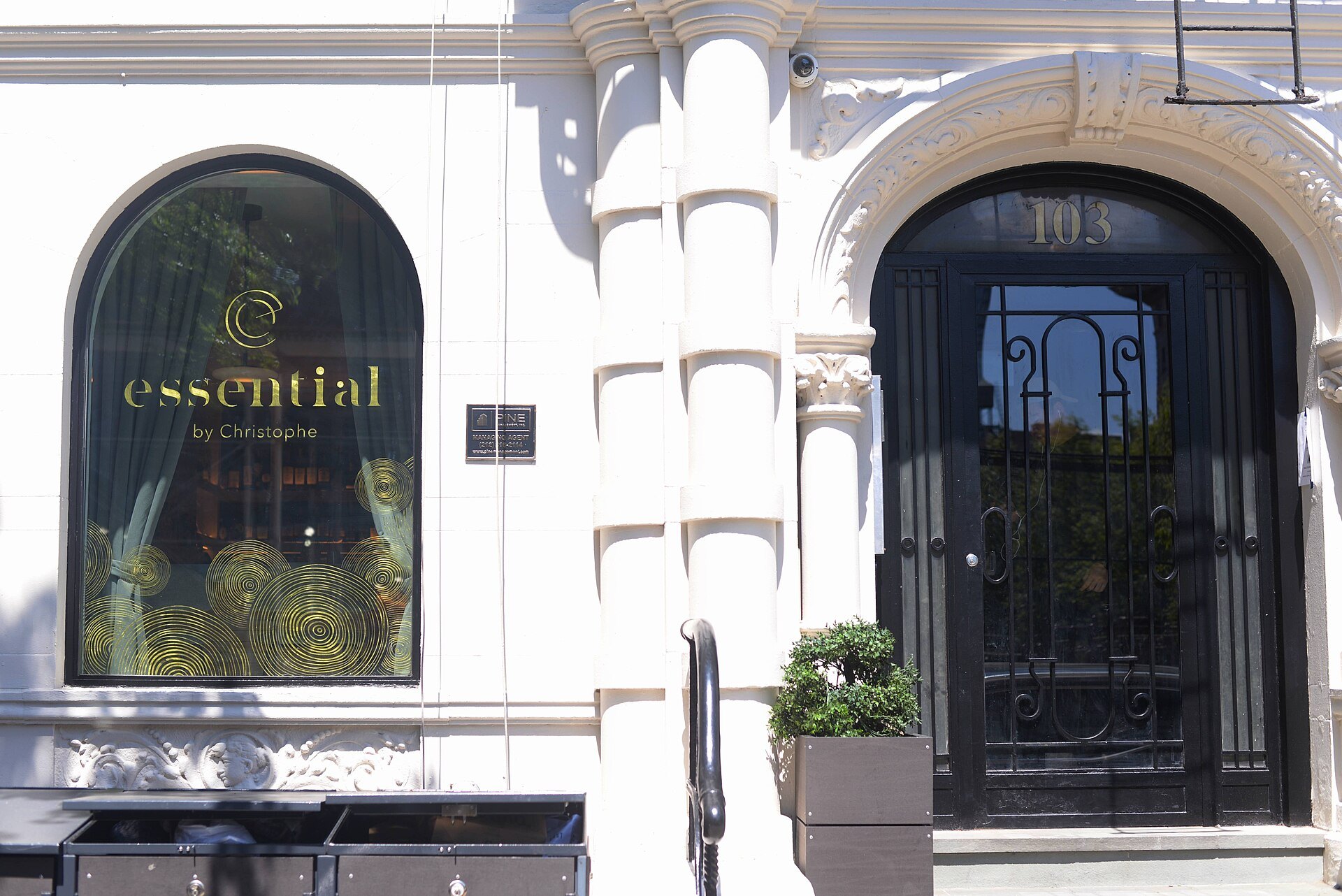Essential by Christophe's arched window and black iron door in a white brownstone on the Upper West Side