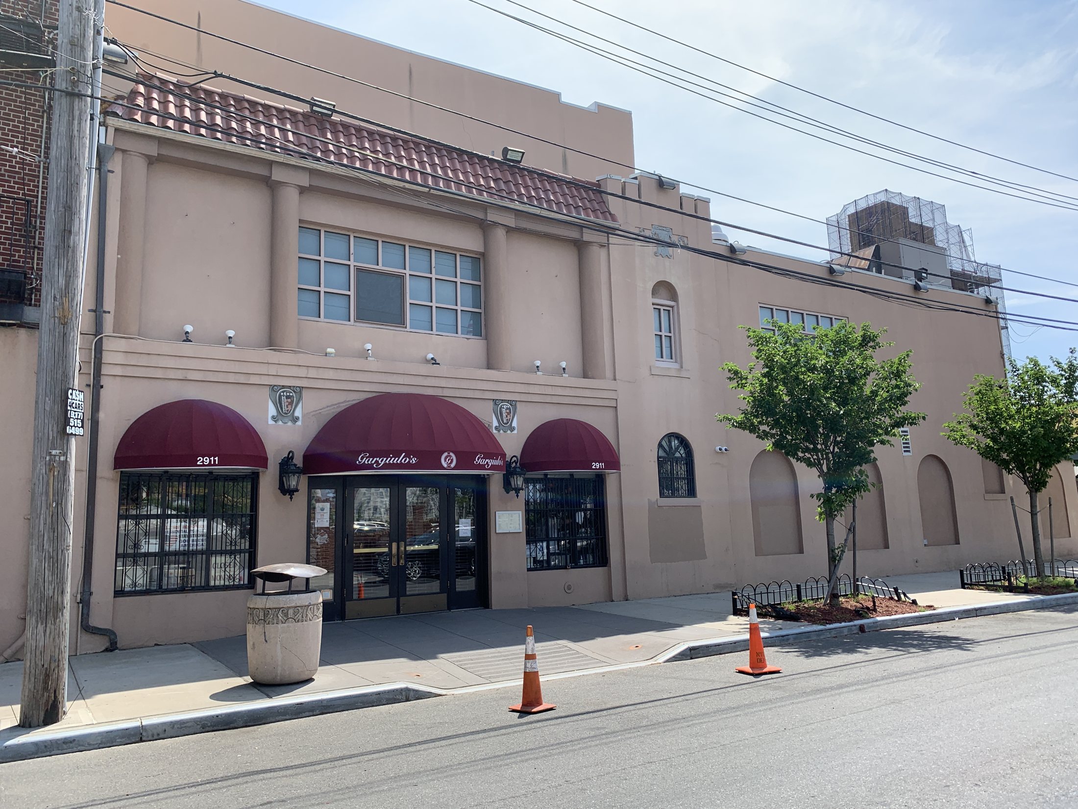 The cream-colored front of Gargiulo's on West 15th Street in Coney Island, with burgundy awnings and a tiled roofline
