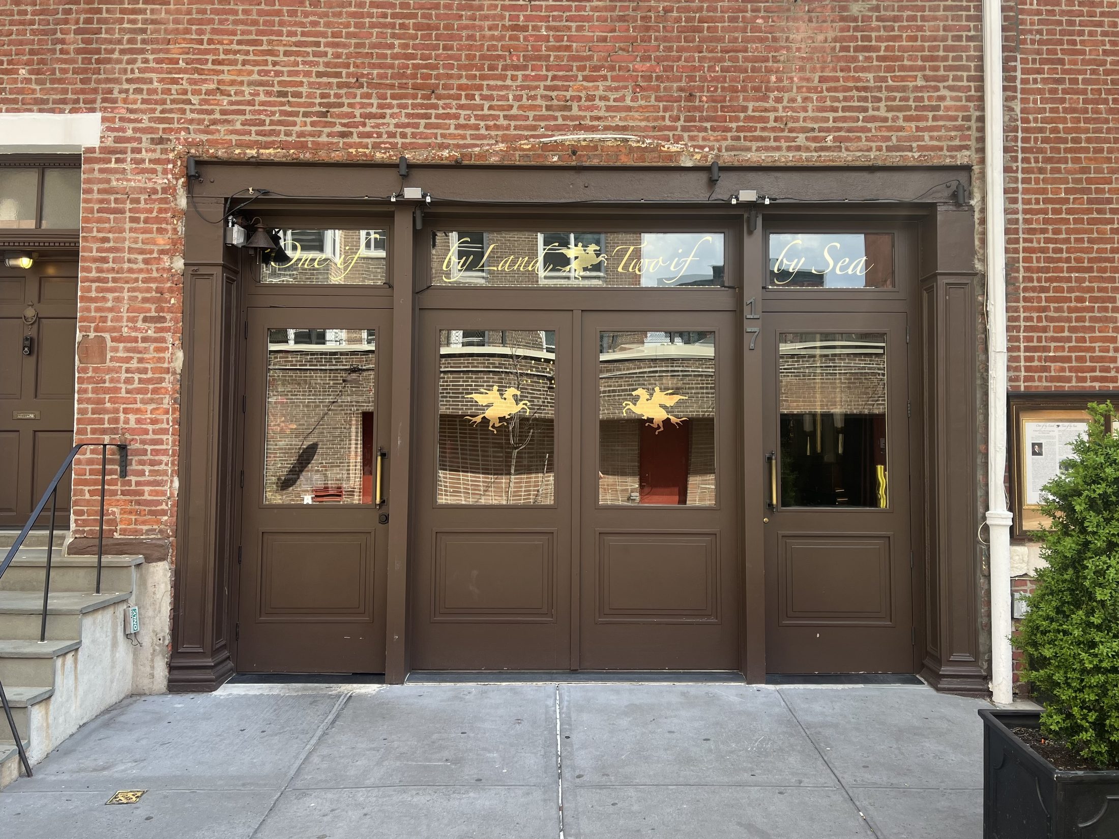 The brown carriage-house doors of One if by Land, Two if by Sea on Barrow Street, with gilded lettering and lantern motifs in the transom glass.