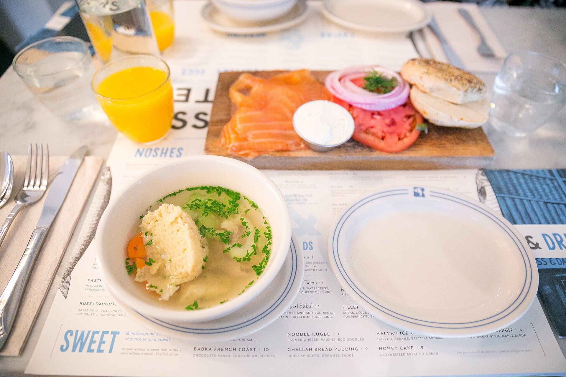 Matzo ball soup, a bagel with lox and fresh orange juice on a table at Russ & Daughters Cafe on Orchard Street