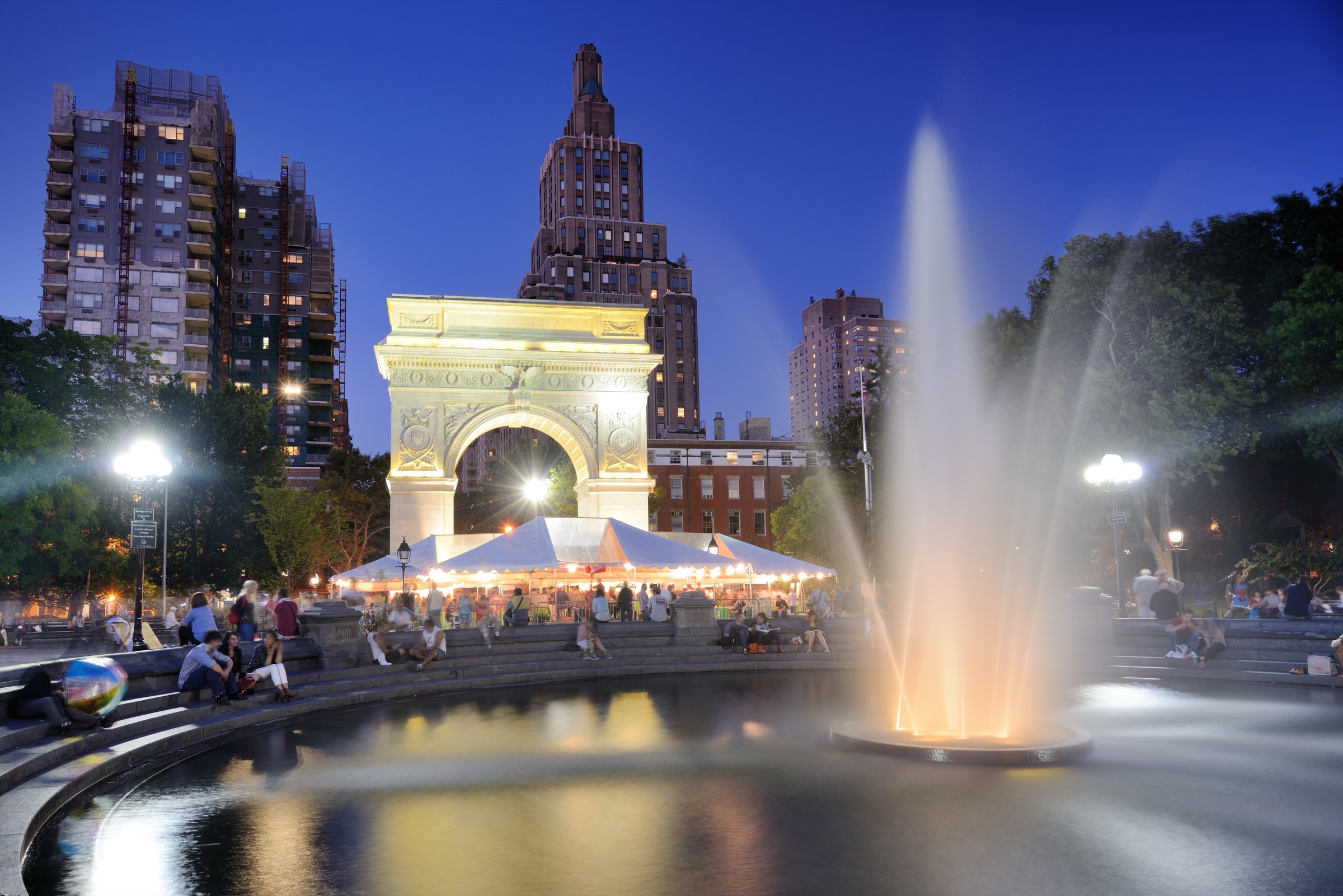Washington Square Arch framing the fountain plaza, with people gathered on the fountain rim